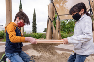 two kids sifting through dig pit