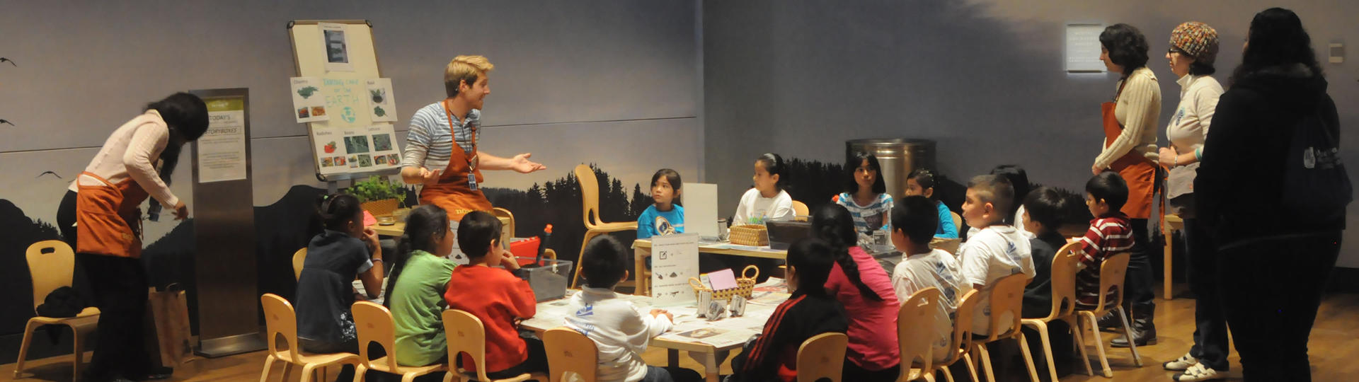 Instructor talking to young children seated around a u-shaped table
