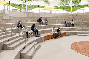 Photo of a group sitting distanced in an outdoor amphitheater watching someone speaking