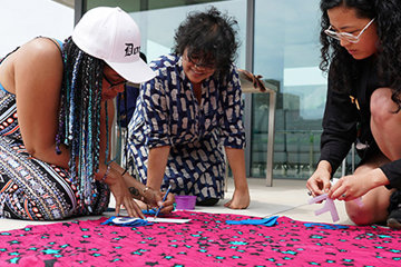 Three women sewing a protest banner