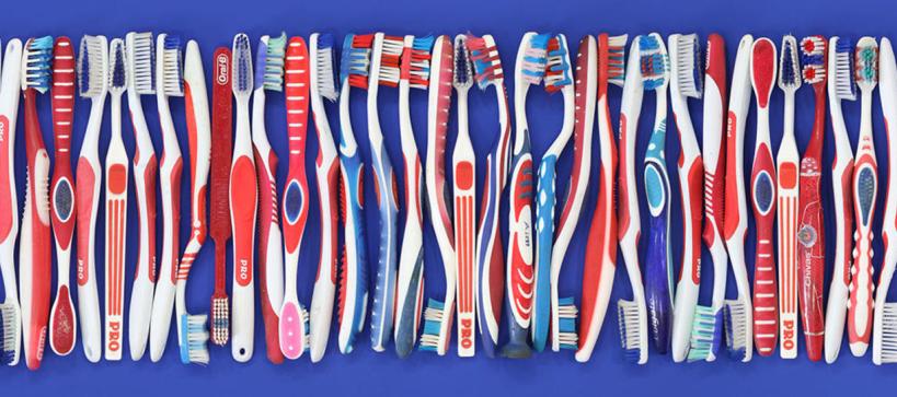 row of plastic toothbrushes, in red, white and blue colors