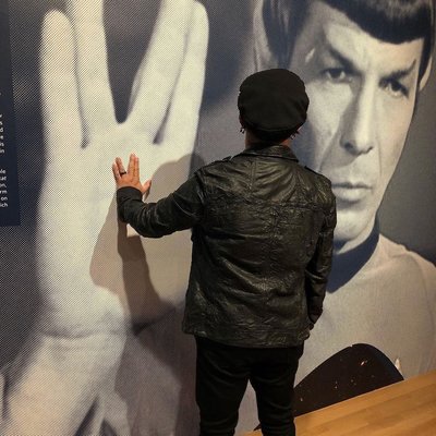Visitor holding up a Vulcan salute against Leonard Nimoy&#039;s as Spock on a wall-sized photo of him