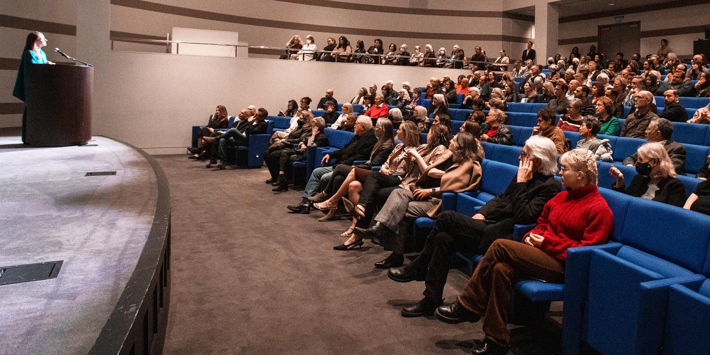 A speaker talking in an auditorium full of engaged adults. 