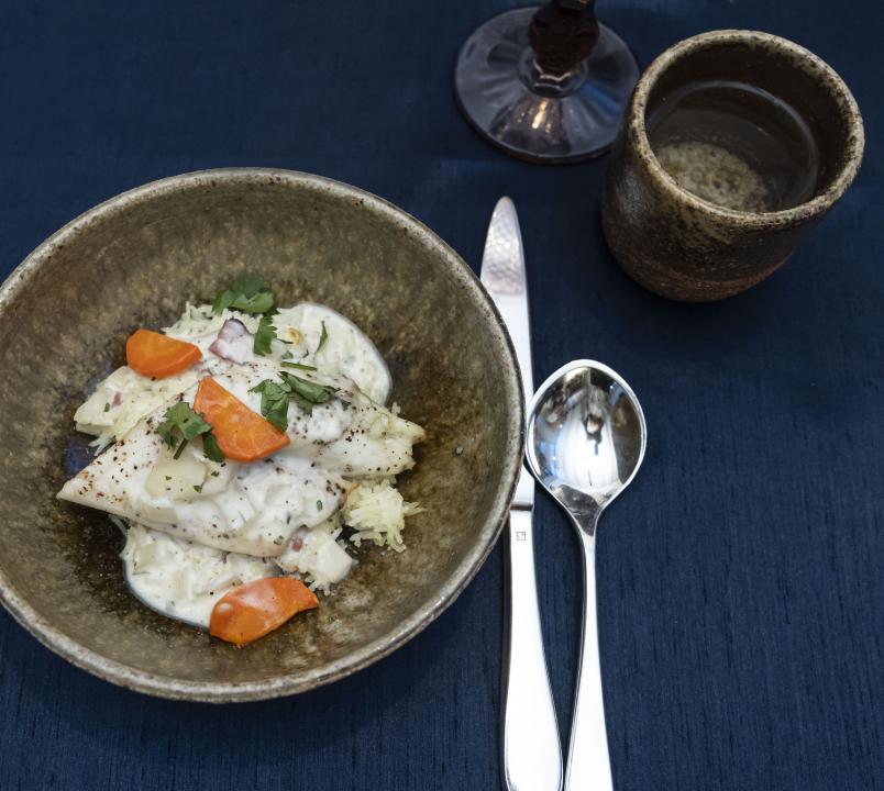 Prepared dish of white fish with orange carrots served in a Common Ground bowl