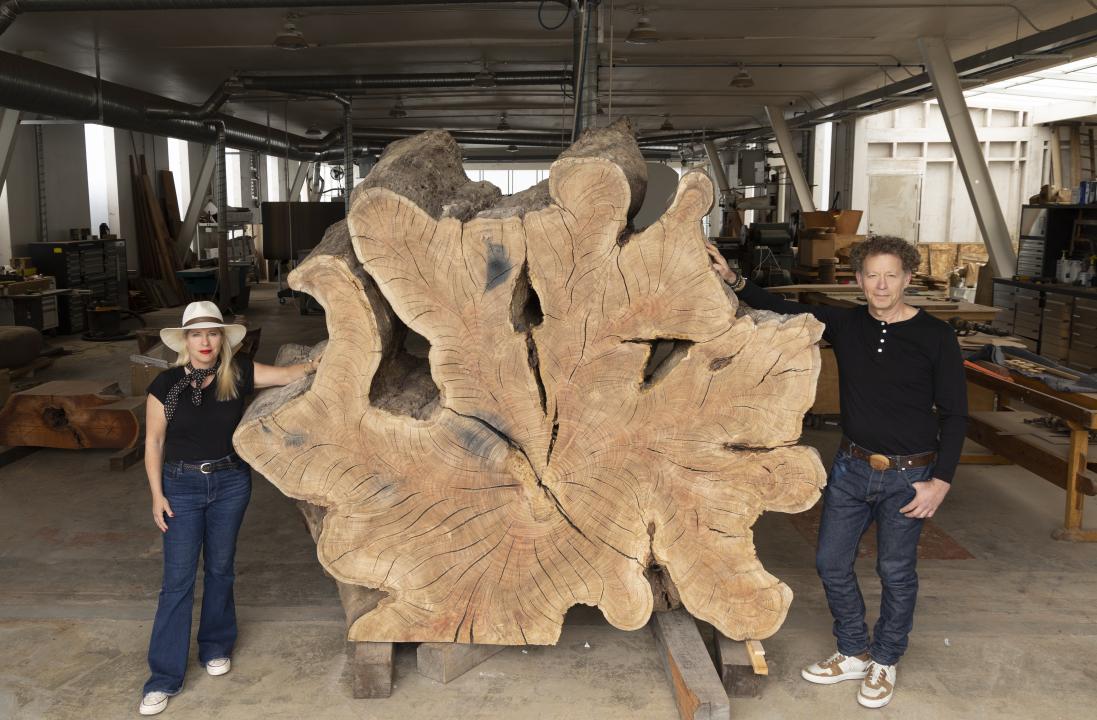 A woman and man stand on either side of a large tree-ring sculpture