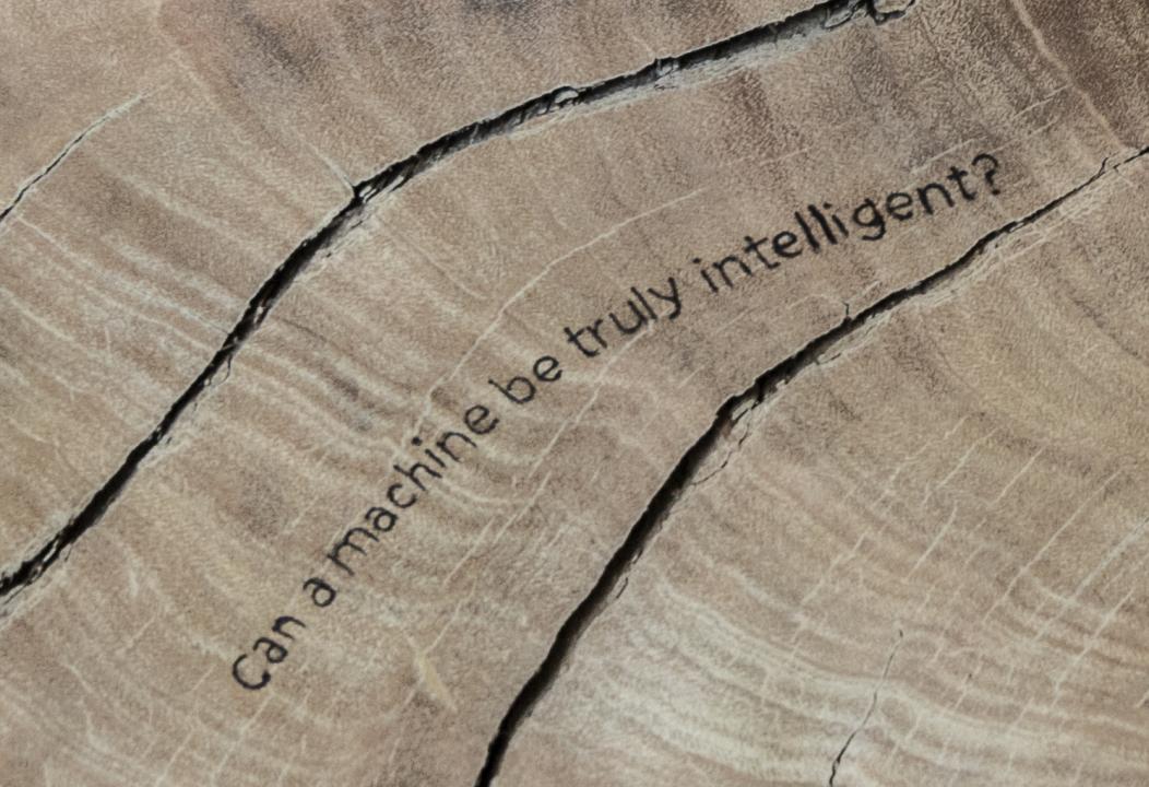 Detail of a tree-ring sculpture that says, "Can a machine be truly intelligent?"