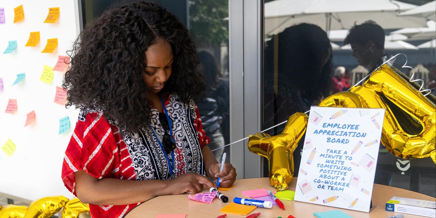 Someone standing at a table fill out Employee Appreciation comments