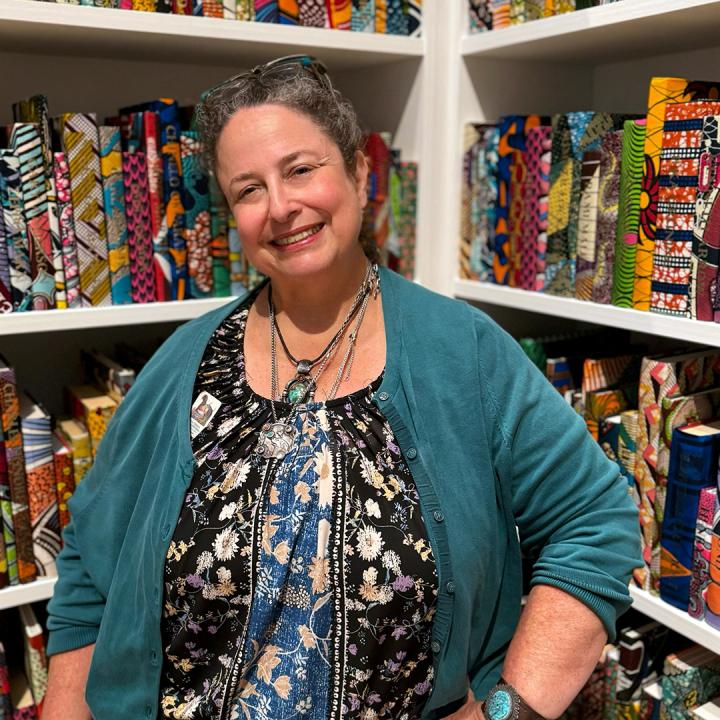 A woman smiling for a portrait in a colorful gallery of books.