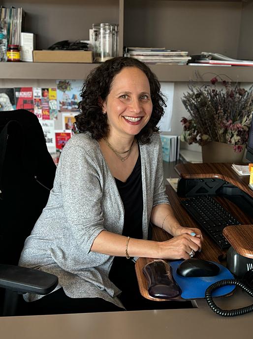 A woman poses for a portrait at a desk computer.