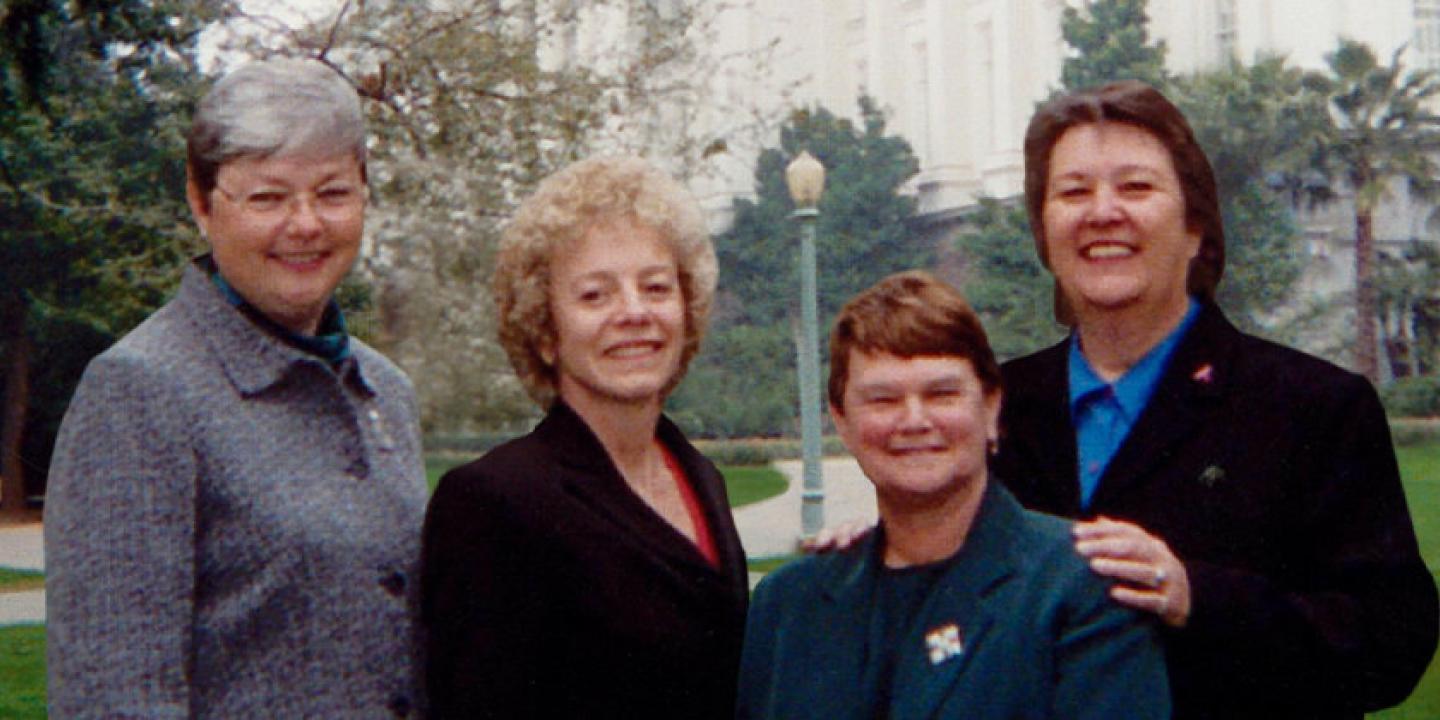 Photo of activists Carole Migden, Sheila Kuehl, Jackie Goldberg, and Christine Kehoe standing together in a green park
