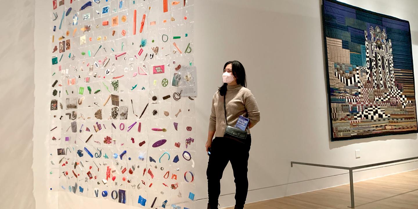One person viewing a untraditional quilt made form plastic with everyday objects sealed in plastic squares