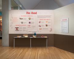 wall in the exhibit that has text and images explaining different types of deli food