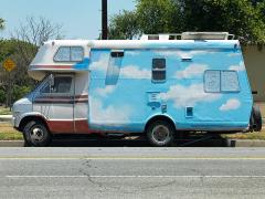 camper with white clouds and blue sky painted on the side of it