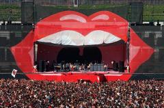 a large crowd of people in front of a stage that is painted with huge open human lips and top teeth