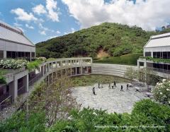 a few people in large courtyard with large pond, buildings on either side of the courtyard