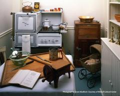 Kitchen interior with old stove, table with cutting board and manual grinder; cupboard