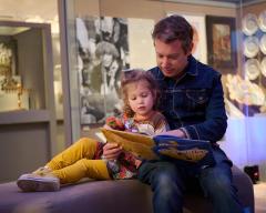 A parent and child sit in Visions and Values reading a book together