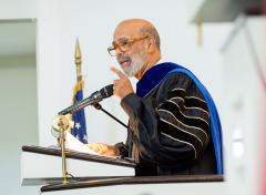 A scholar talking in a microphone at a podium.