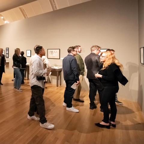 Groups of museum visitors looking at art on sprawling gallery walls