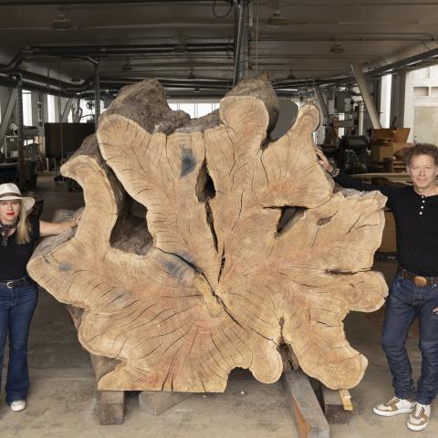 A woman and man stand on either side of a large tree-ring sculpture