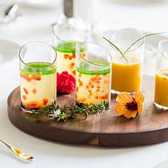 Several glasses of exotic mixed drinks on top of a round wooden serving board