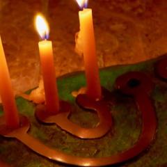 Hanukkah lamp on a flat stone with six, white candles burning