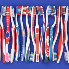 row of plastic toothbrushes, in red, white and blue colors
