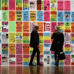 people looking at a wall filled with colored typography posters