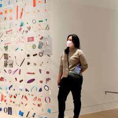 One person viewing a untraditional quilt made form plastic with everyday objects sealed in plastic squares