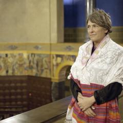 A person wearing a prayer shawl stands with hands clasped