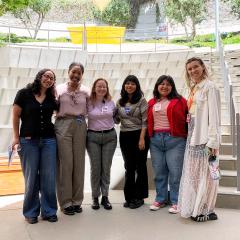 Six women standing in an amphitheater smiling for a photo together.