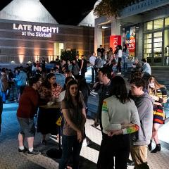 A crowd gathered in front of a building with the words, Late Night at the Skirball" projected on the building.