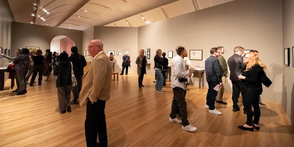 Groups of museum visitors looking at art on sprawling gallery walls